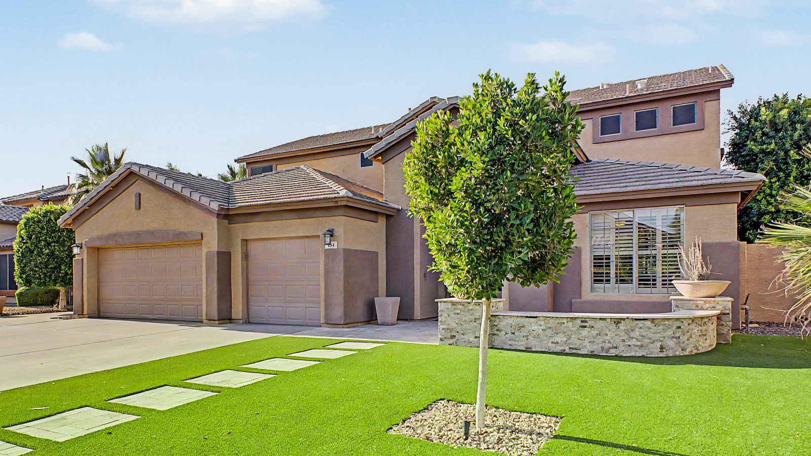 A single-story East Valley home with tidy desert landscaping and a green front lawn